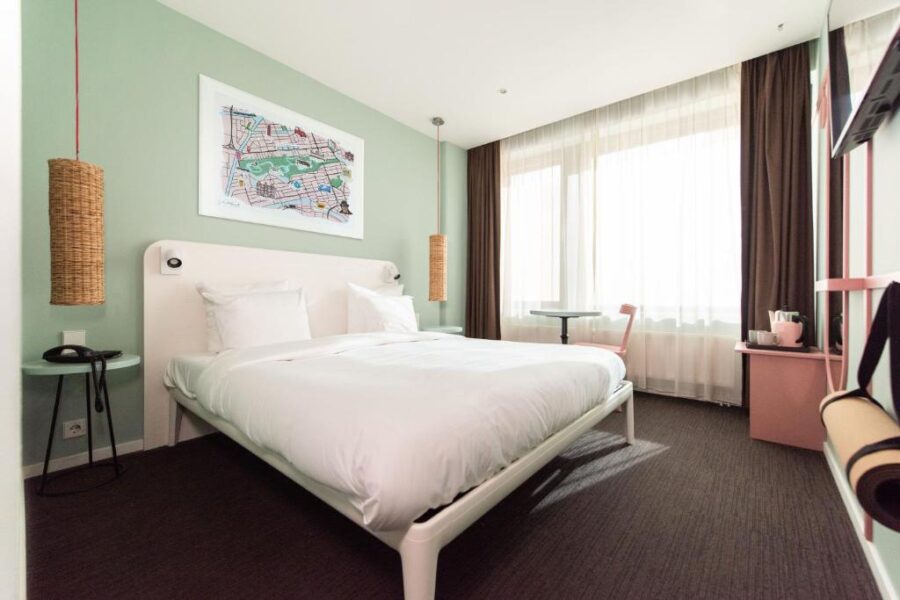 Interior of a Conscious Hotel Vondelpark room with a bed, desk, and wall art, creating a cozy atmosphere.