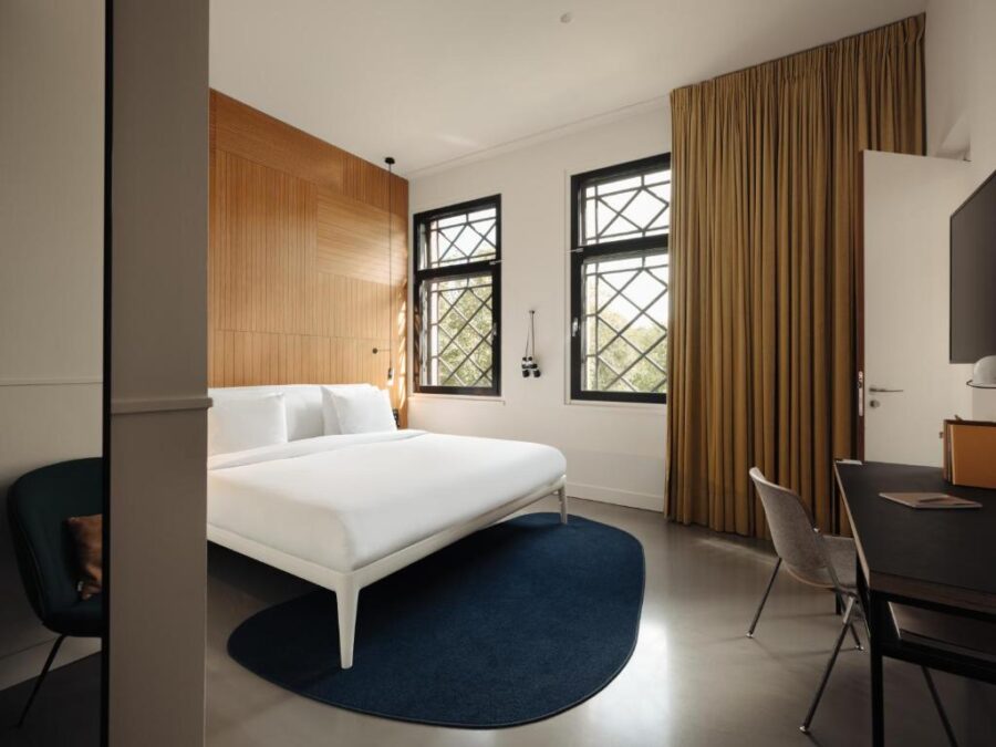 Hotel room at Conscious Hotel Westerpark in Amsterdam featuring a bed, desk, and a large window with natural light.