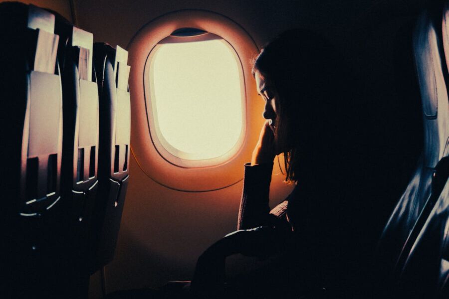 Woman on airplane gazing out window, strategic napping
