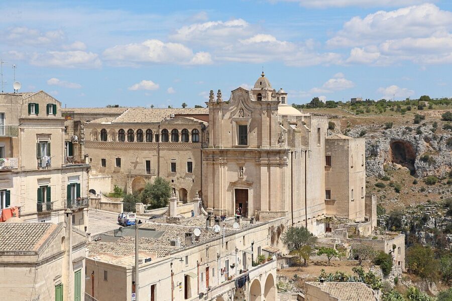 Scenic view of the Convent of Saint Agostino and a nearby building atop a hill in Matera, Italy, under bright sunlight.
