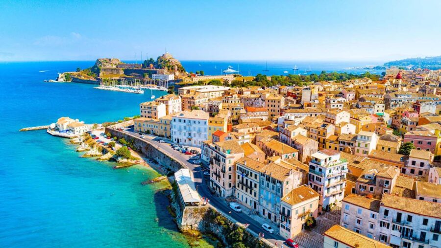 Aerial view of coastal town Corfu, featuring turquoise waters, charming architecture, and historic castle.