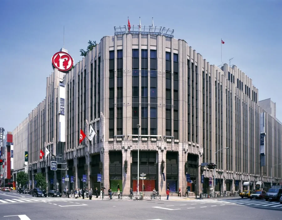 Isetan Shinjuku department store on a bustling Tokyo corner with pedestrians and taxis.