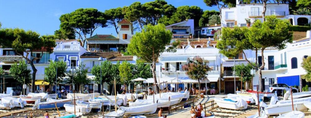 Row of boats docked in a serene harbor along the Costa Brava coastline in Spain.
