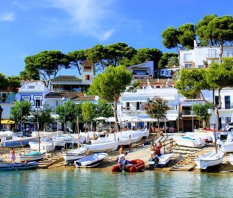 Row of boats docked in a serene harbor along the Costa Brava coastline in Spain.