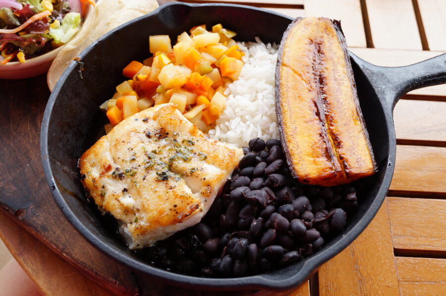 Traditional Costa Rican Casado meal featuring rice, beans, plantains, and grilled fish on a colorful plate