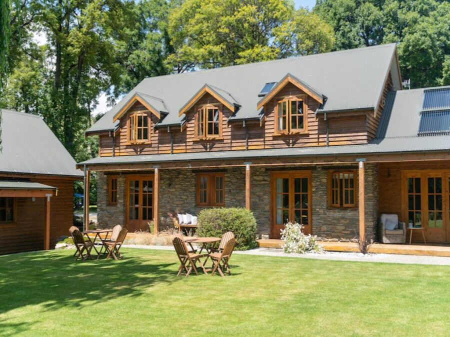 Rustic countryside lodge with solar roof, wooden dormers and garden lawn with outdoor seating.