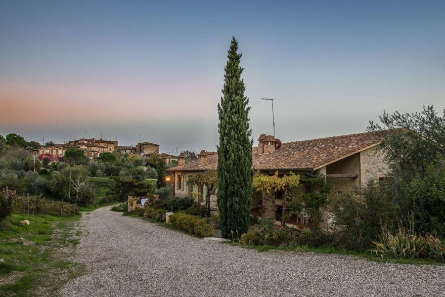 Rustic stone house with terracotta roof and garden during serene countryside twilight.