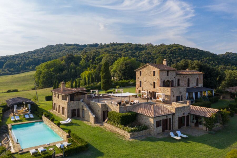 Tuscan villa with pool, terracotta roofs, gardens, and hills, offering serene countryside escape.