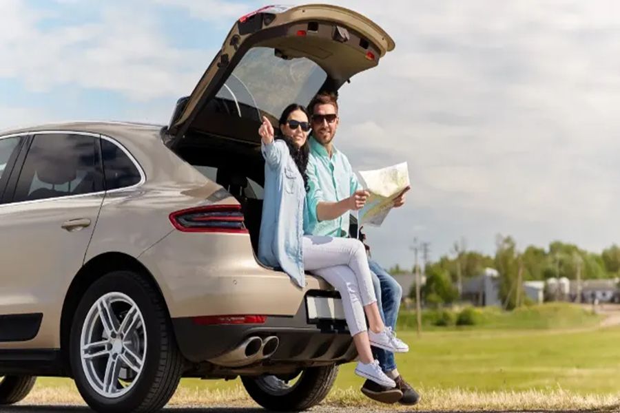 Young couple on SUV tailgate embracing natures freedom during a road trip adventure.
