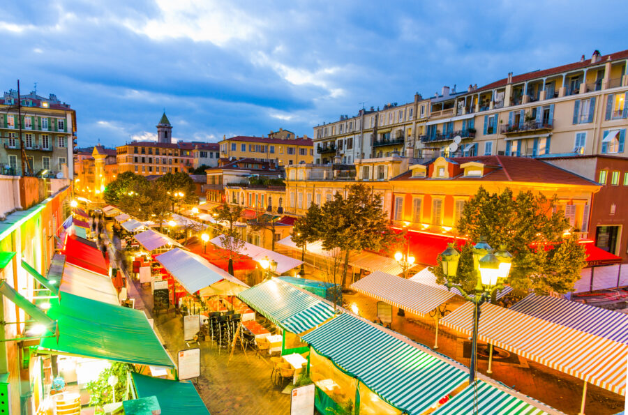 Night view of Cours Saleya in Nice, France, illuminated by streetlights with vibrant market stalls and lively atmosphere