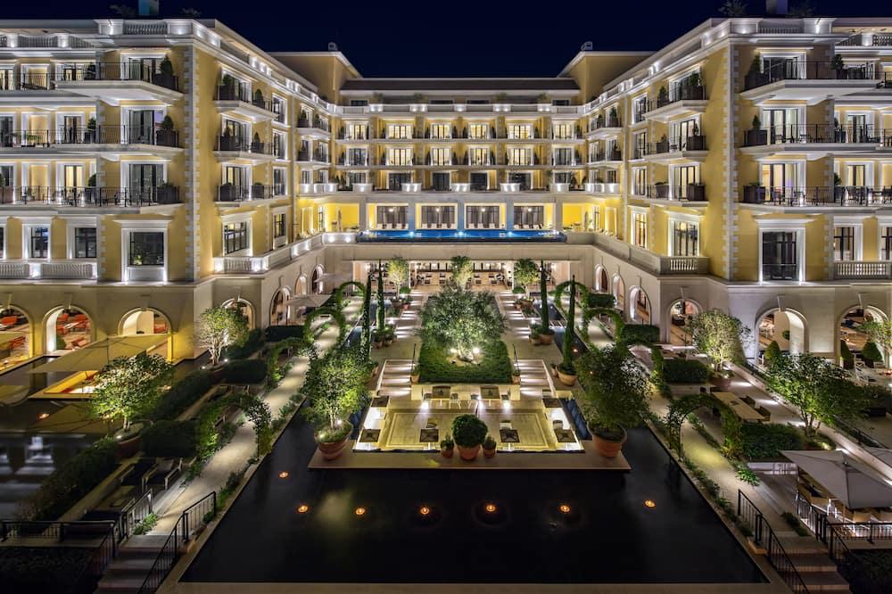 Luxurious Tivat hotel at night with garden, infinity pool, elegant architecture.