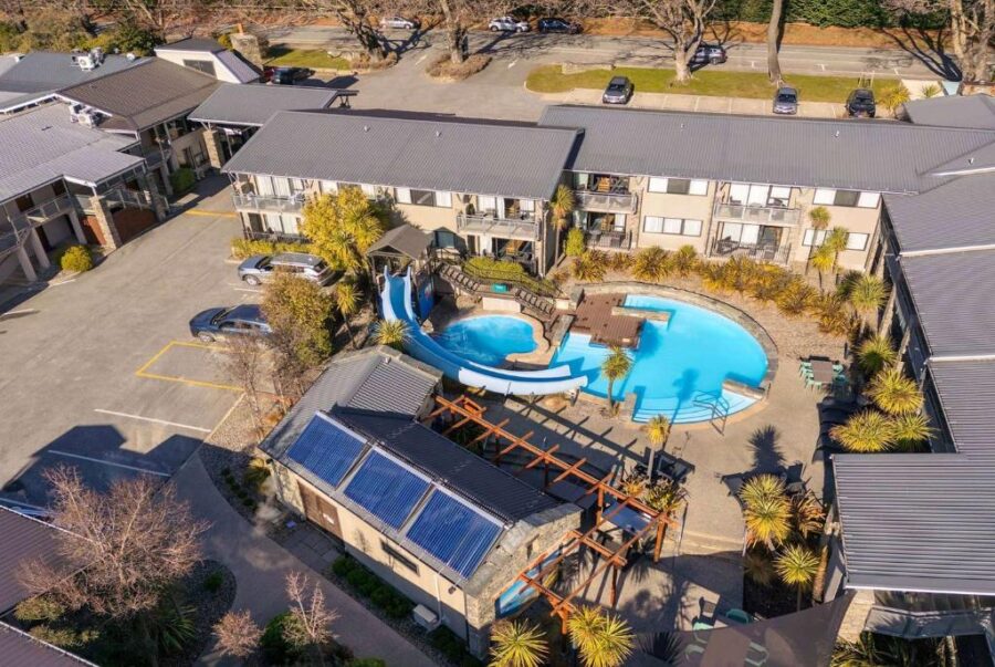 Aerial view of Club Wyndham Wanaka resort courtyard with outdoor pool, water slide, and solar panels.