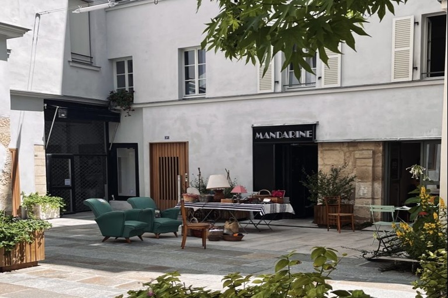 Village Saint-Paul courtyard with Mandarine shop, outdoor furniture, market display and potted plants.