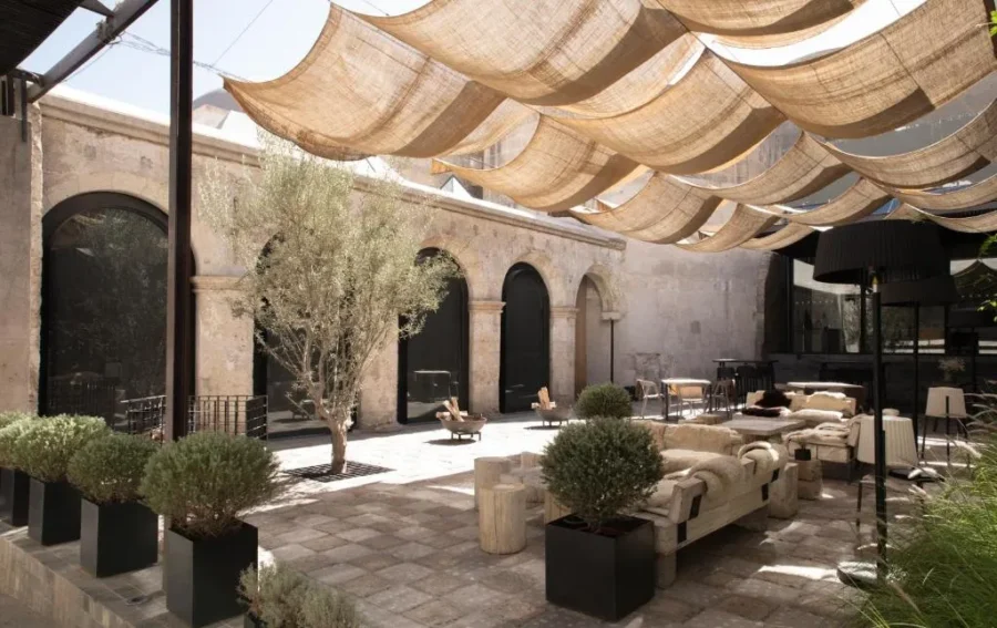 Luxury stone courtyard lounge in Arequipa with arches, canopy shade, and modern outdoor seating.