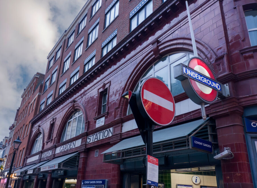 Covent Garden tube station entrance in London, showcasing its iconic sign and lively atmosphere of commuters