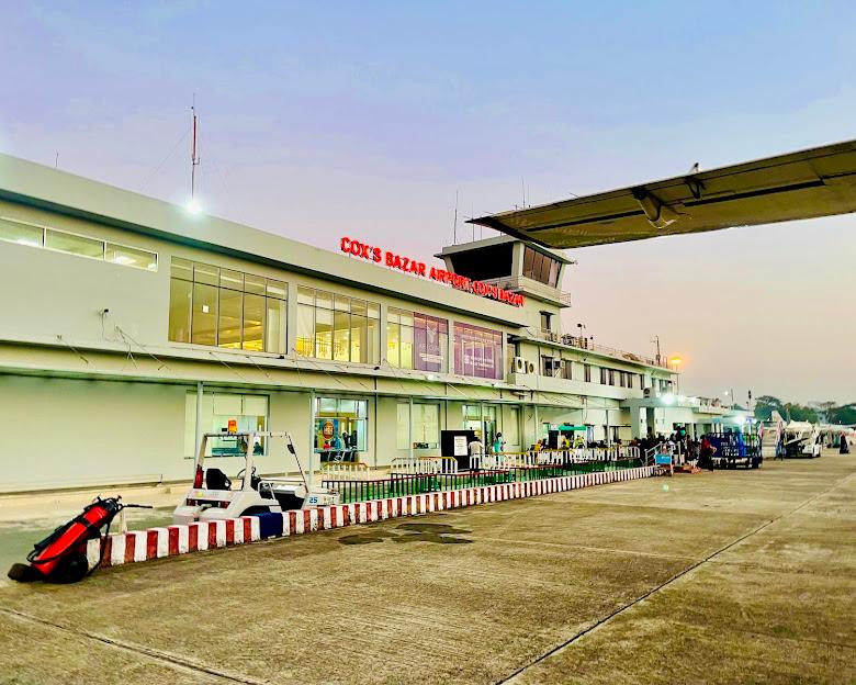 Coxs Bazar Airport terminal at sunrise, featuring modern design and active passenger scene.