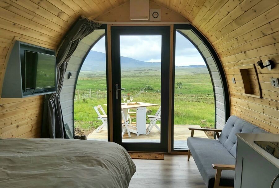 Modern cabin retreat with curved design, wood interior, glass door, and scenic nature views.