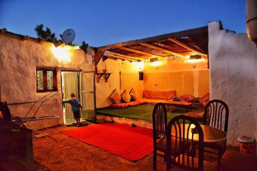 Cozy Bedouin outdoor lounge at adobe house during blue hour with cushions, chairs and warm lights.