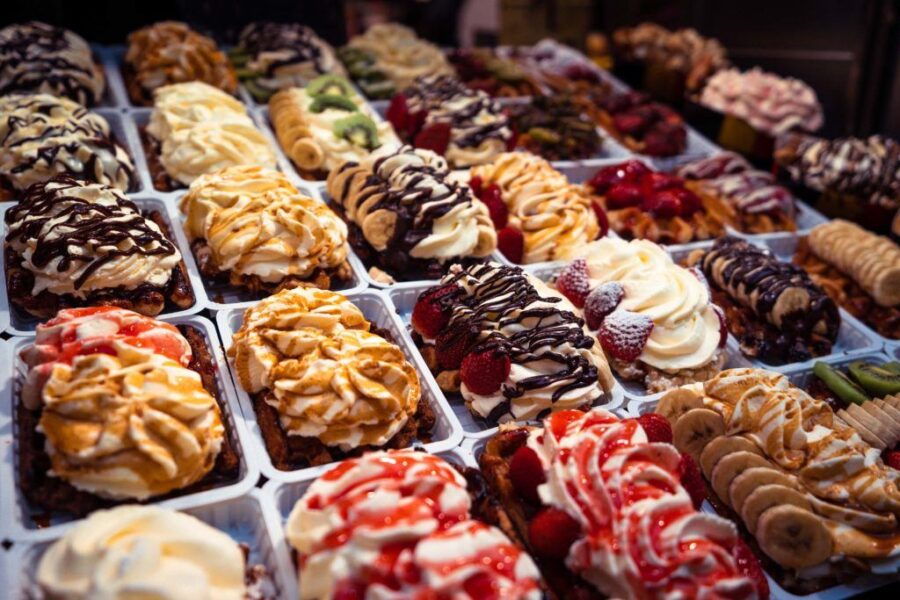 Belgian waffle desserts with cream, strawberries, chocolate drizzle arranged in neat bakery rows.