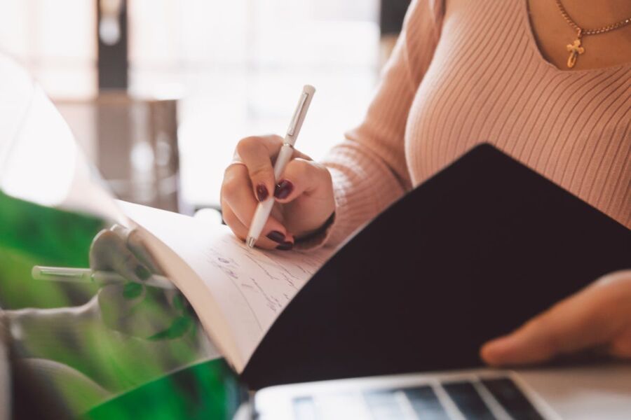 Person engaged in writing at a well-lit desk, blending traditional and modern elements.