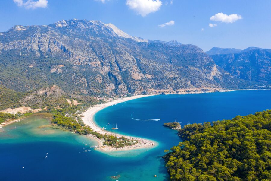 Aerial view of Lycian Way crescent beach and turquoise lagoon on Turkeys rugged coastal bay.
