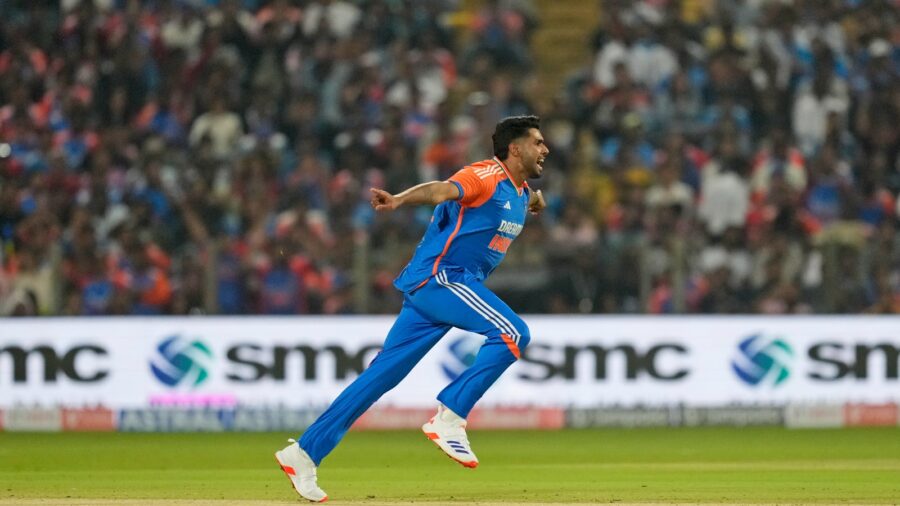 Cricket player celebrates triumphantly on the field with joyful crowd in stadium.