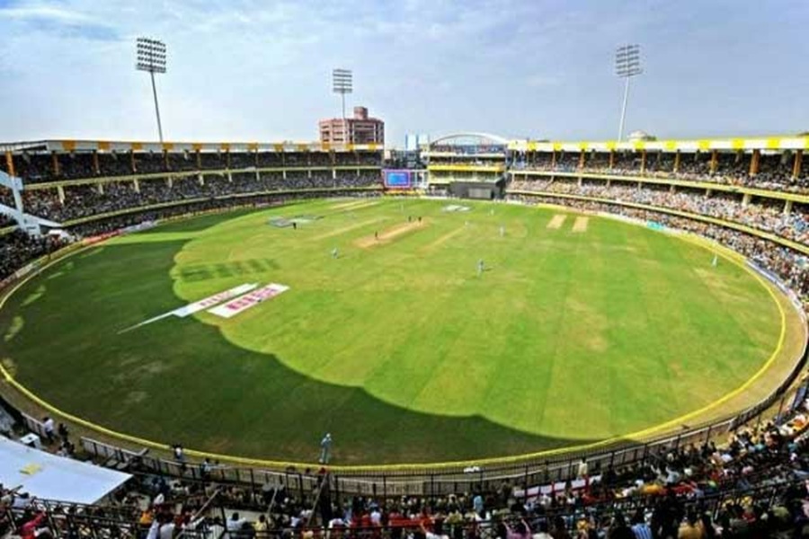 Cricket match at vibrant stadium with energetic crowd, modern design, and digital scoreboard.