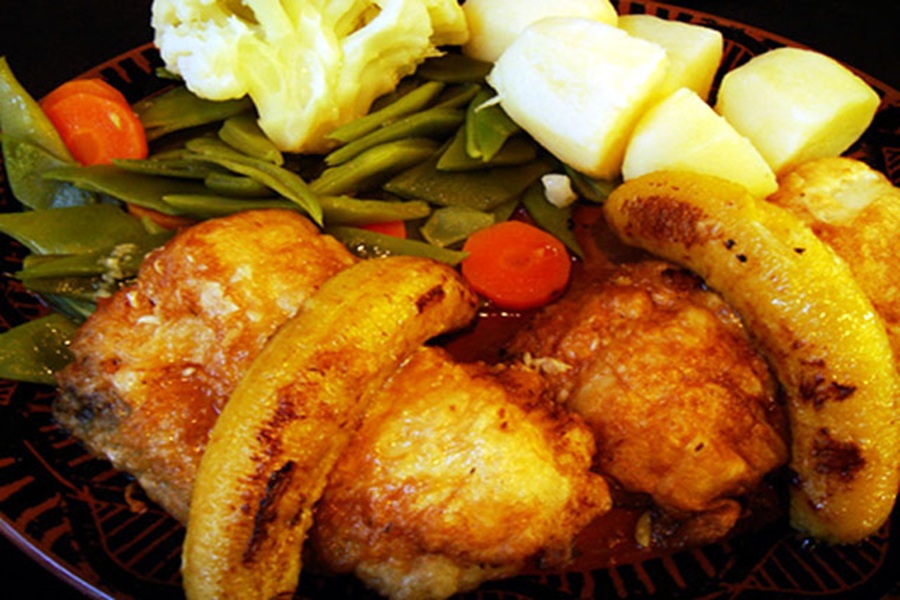 Crispy fried fritters with plantains, vegetables, potatoes, and gravy.