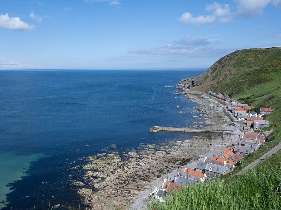 Scenic view of Crovie, Aberdeenshire, featuring a small town by the coast and the expansive Moray Firth behind it.