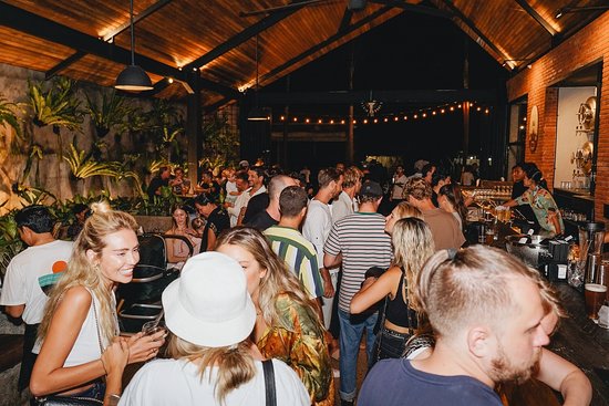 Crowded brewery bar nightlife scene with people drinking, socializing, and enjoying a rustic modern venue.