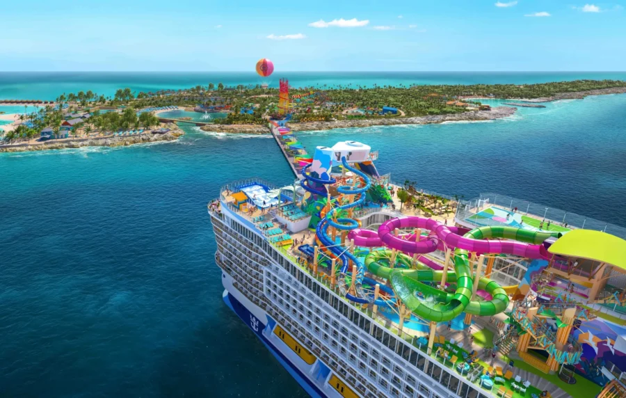 Luxury cruise docked at tropical paradise with water slides, beach, and vibrant amenities.
