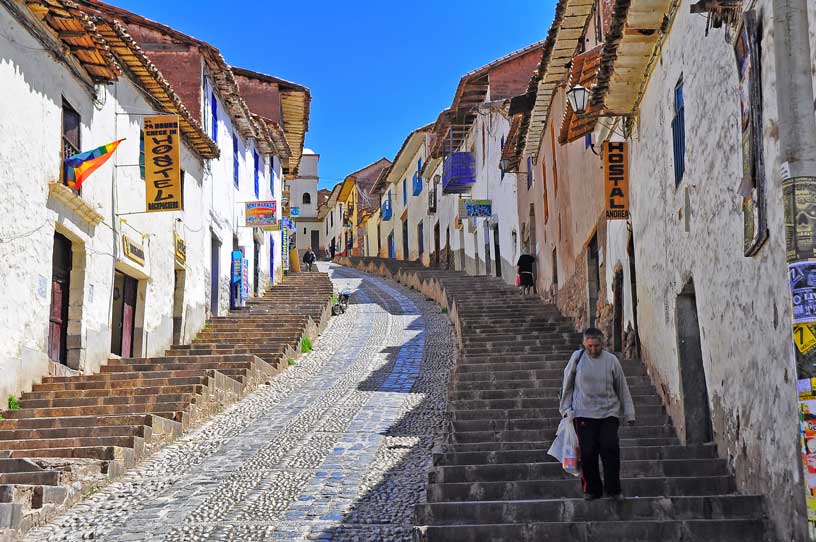 Man walks down the stairs of Cuesta de Santa Ana, a narrow street in Cusco, Peru, lined with traditional architecture.
