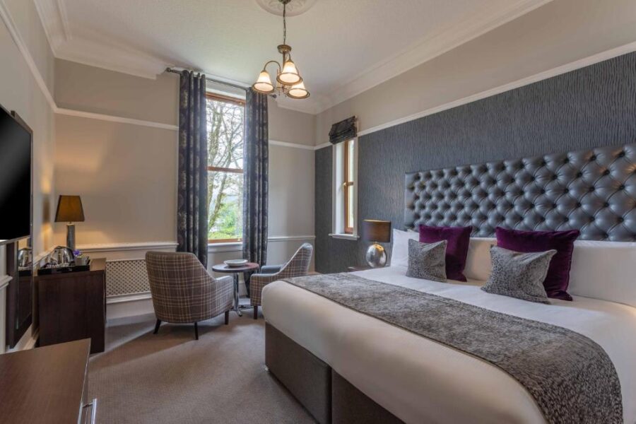 Interior of a hotel room at Cuillin Hills Hotel, Isle of Skye, showcasing a spacious bed and a flat-screen television.