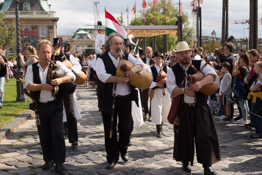 Traditional musicians performing festive music at cultural event with historical architecture.