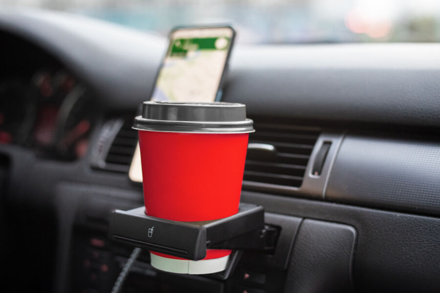 Cup of coffee securely placed in a car's cup holder, positioned near the steering wheel for easy access while driving