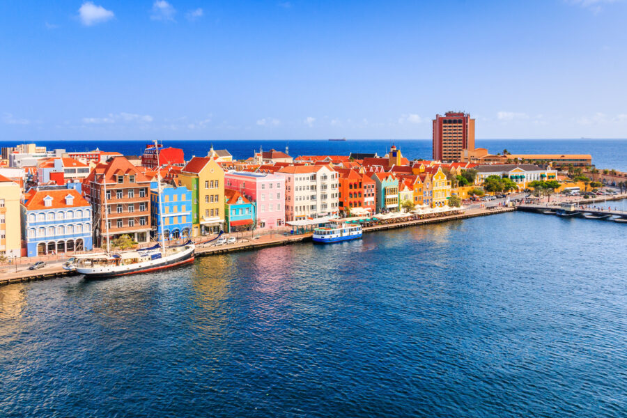 Scenic panorama of Curacao, featuring lush greenery, turquoise waters, and charming buildings typical of the Caribbean.
