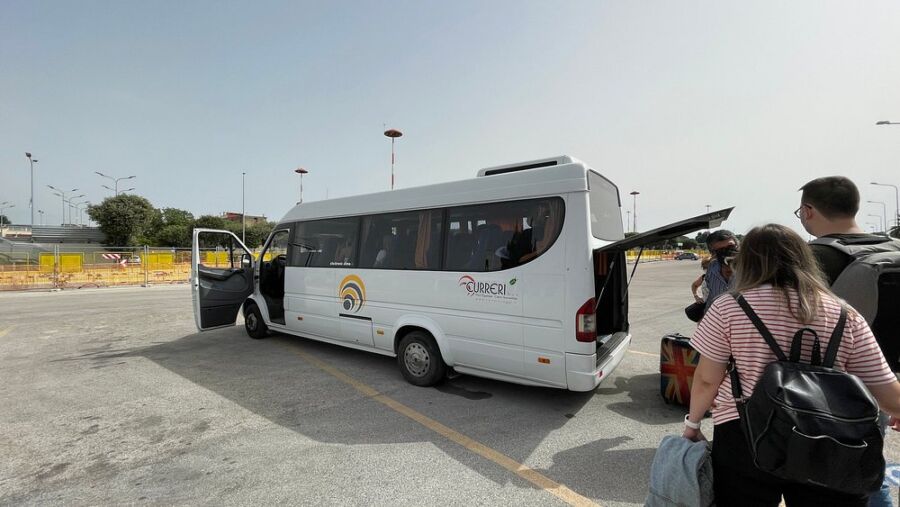 Passengers boarding a Curreri Viaggi bus, carrying luggage and preparing for departure.
