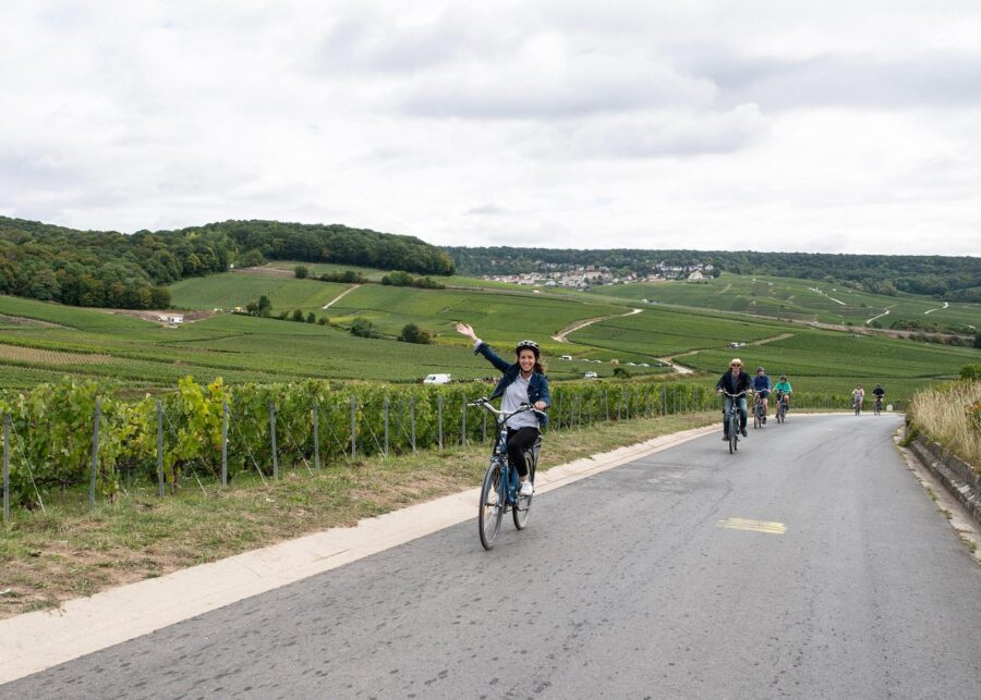 Cyclists riding a country road through Hautvillers vineyards and rolling hills.