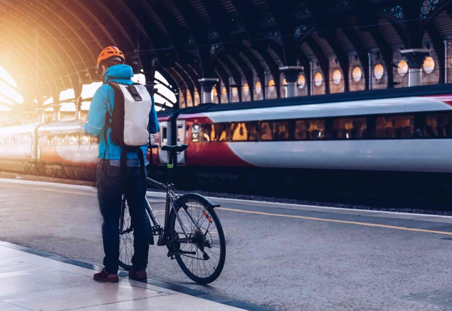 Cyclist in vibrant gear at ornate train station, showcasing urban mobility and architectural beauty.