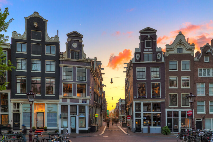 Sunset over Amsterdam's nine little streets, showcasing iconic Dutch architecture and vibrant colors in the sky.