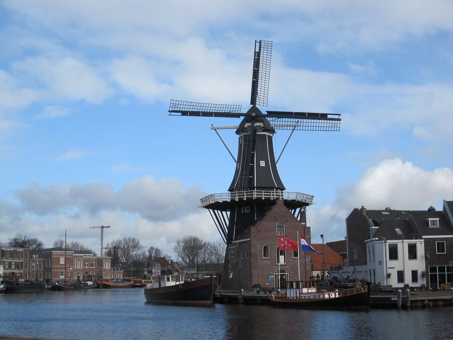The De Adriaan Windmill stands tall beside a large body of water in Haarlem, Netherlands, showcasing its historic architecture.