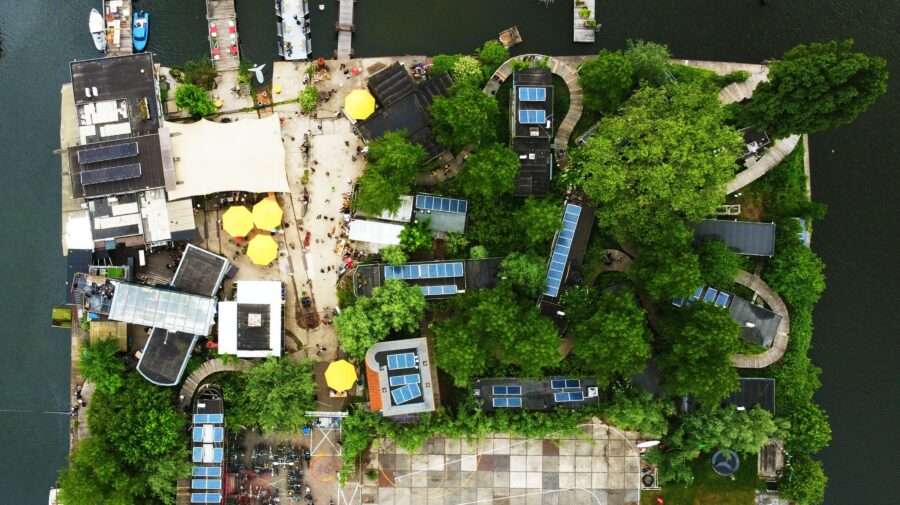Aerial view of De Ceuvel Amsterdam, showcasing a small, tree-covered island surrounded by water.