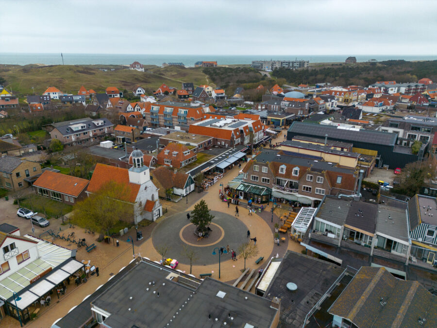 Aerial view of de Koog city center in Texel, featuring a church and square, surrounded by the Wadden Sea.