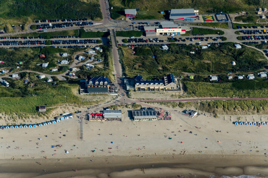 Aerial view of the Strand beach in De Koog, Texel, Netherlands, showcasing sandy shores and vibrant blue waters.
