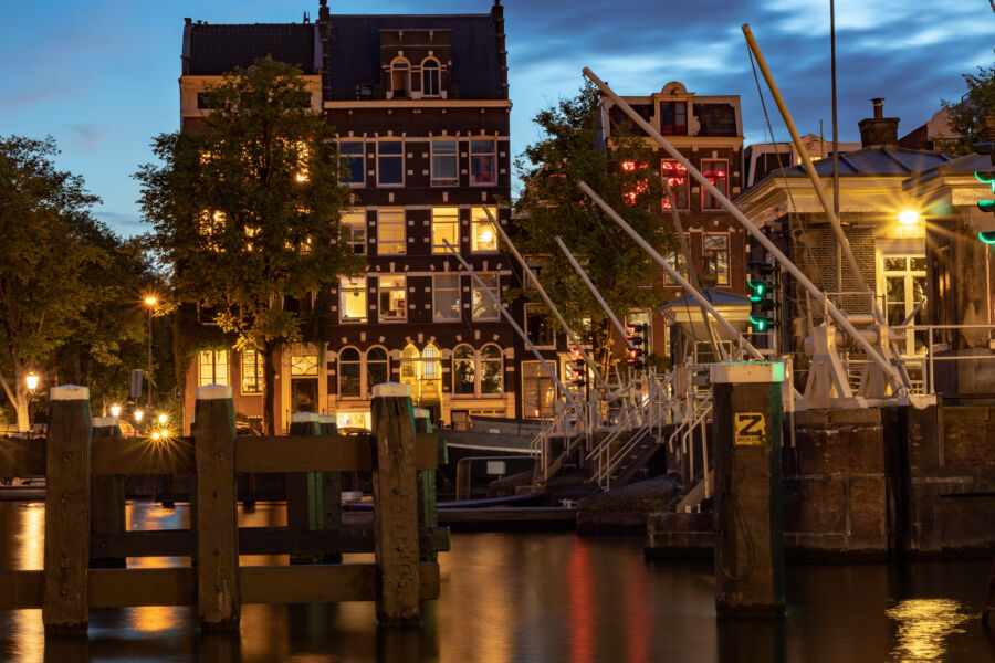 Evening scene of the Amstel River in Amsterdam, featuring the De Pijp district illuminated by twilight hues and gentle reflections