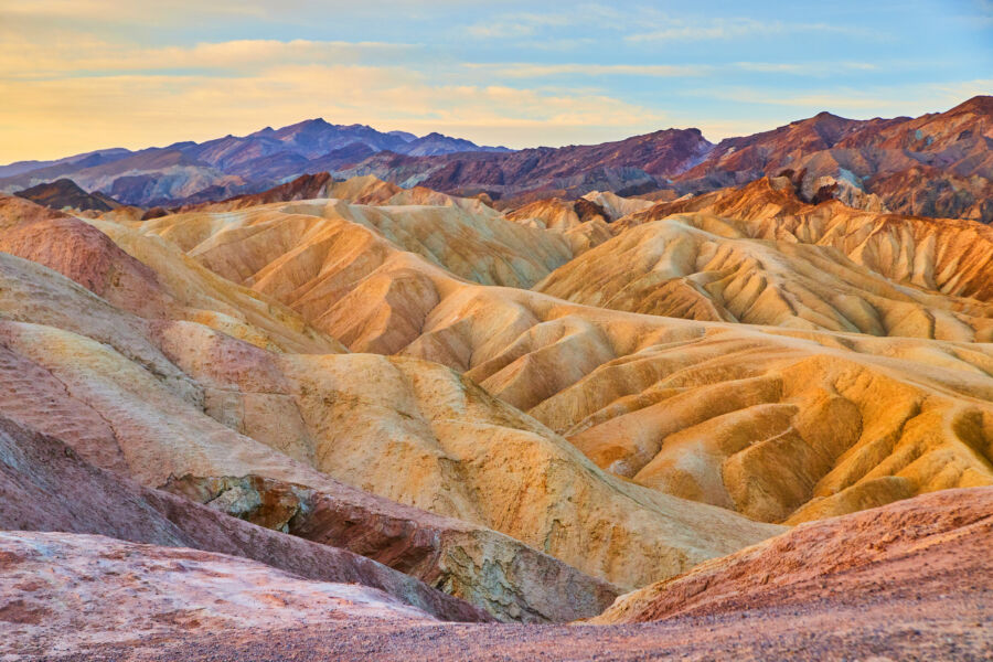 Vibrant sunrise over Zabriskie Point in Death Valley, highlighting the colorful sediment formations of the stunning terrain