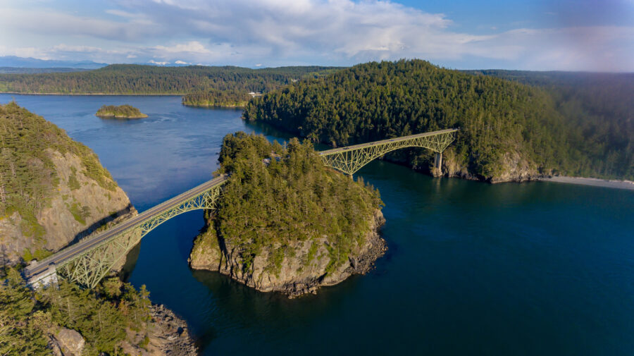 Aerial view of Deception Pass Bridge in Washington State, connecting Whidbey Island to the mainland with dramatic cliffs nearby.
