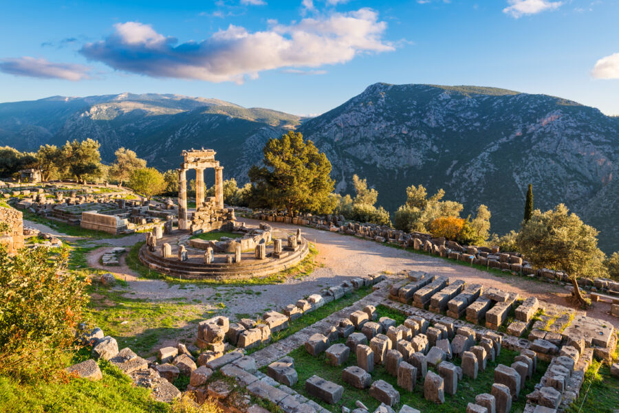 Temple of Athena Pronaia in ancient Delphi, Greece, showcasing classical architecture against a mountainous backdrop.
