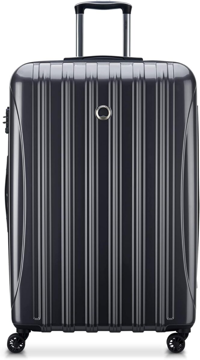 Black DELSEY PARIS Helium Aero hardside suitcase with wheels on a white background.