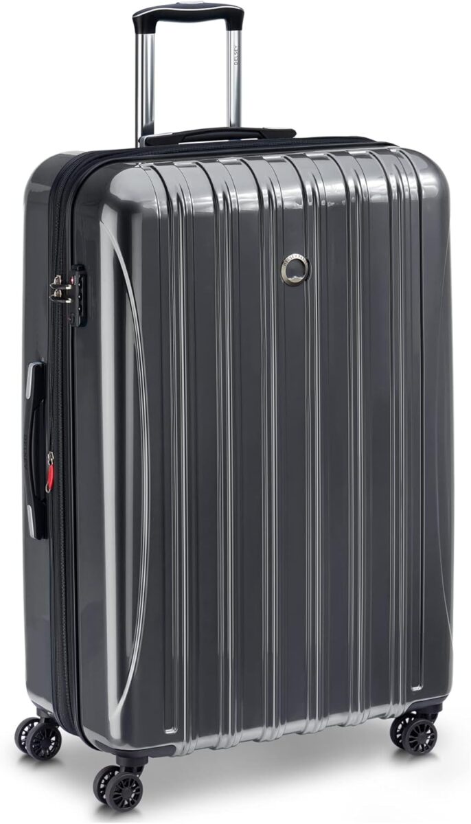 Large black DELSEY PARIS Helium Aero suitcase with wheels on a white background, showcasing its hardside expandable design.